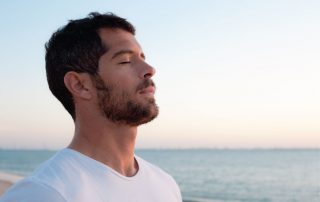 Mind Your Body Co - Man deep breathing in front of ocean